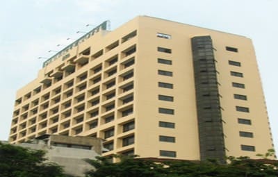 Pinnacle Hotel on Rama 4 Road: a cream-coloured mid-rise hotel block with recessed balconies above trees