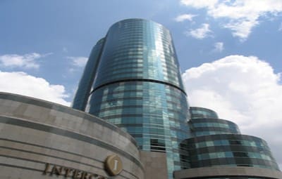 Curved blue glass tower rising behind a stone podium bearing an InterContinental Bangkok sign