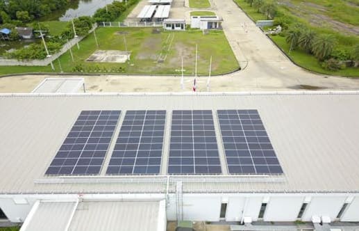 Aerial close view of four blocks of solar panels on a pale metal roof