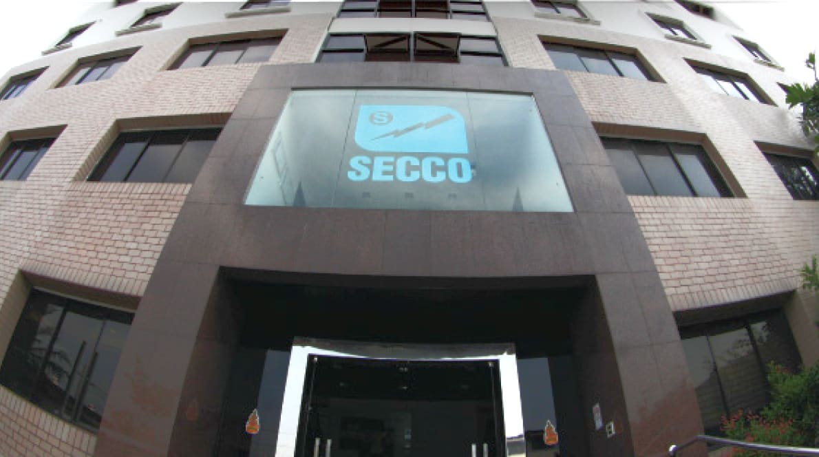 Entrance of the SECCO head office, a brick-clad building with the SECCO logo on a large glass panel