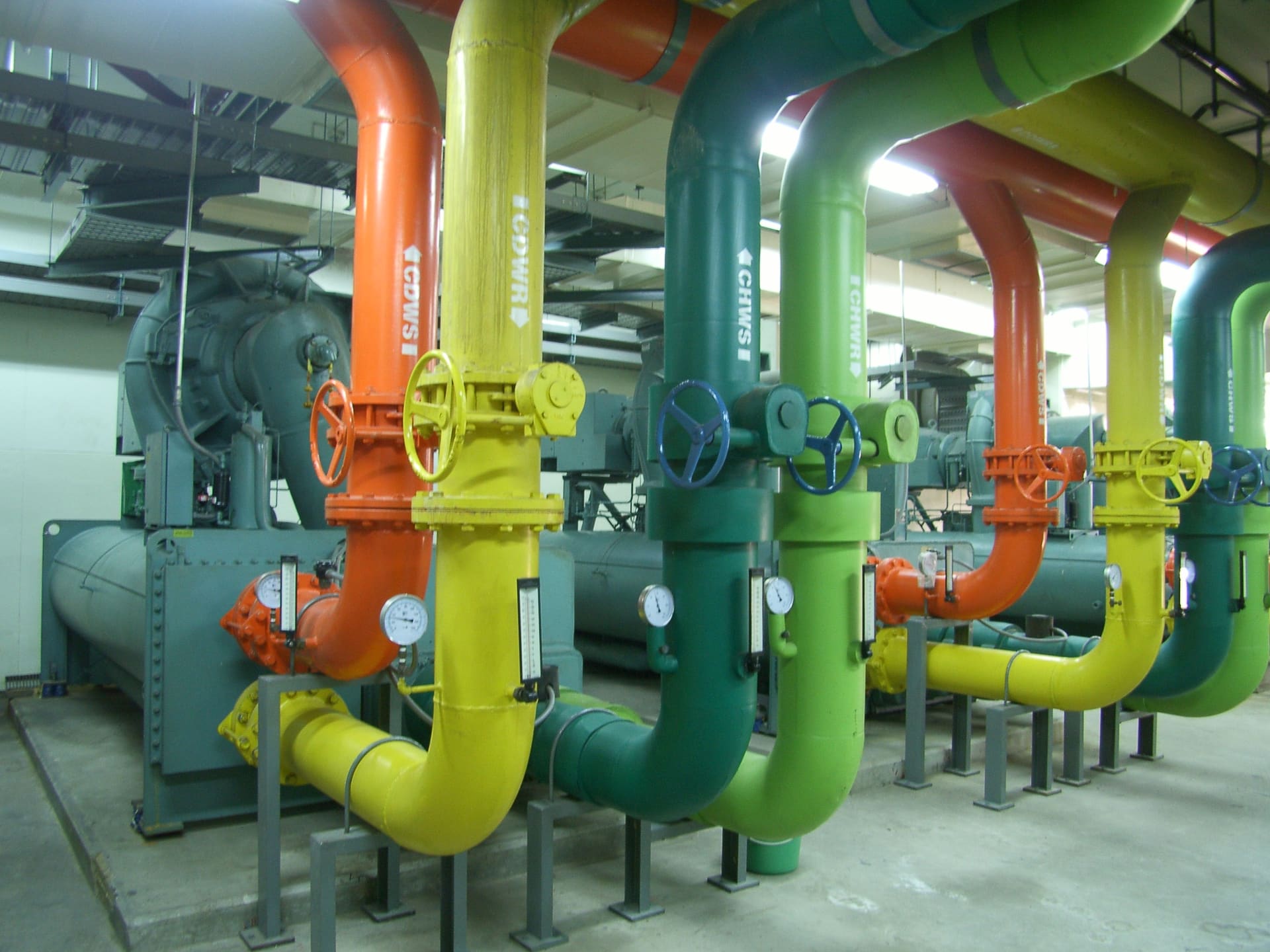 Chiller plant room with colour-coded chilled-water and condenser-water pipes and valves